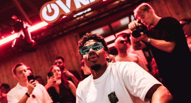 Dj Menesix draait muziek in een clubomgeving met publiek.