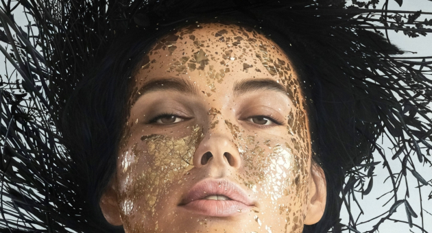 Een portret van een persoon met gouden schmink op het gezicht.