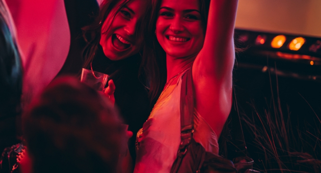 Two women smiling and raising their arms in a festive setting.