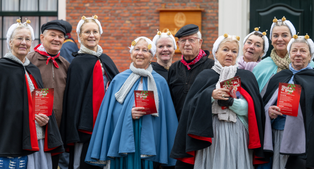Five women and one man in traditional attire, smiling and posing.