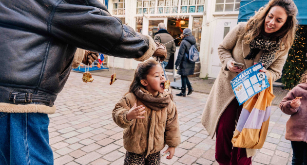 Een meisje probeert een lekkernij van een draad te eten