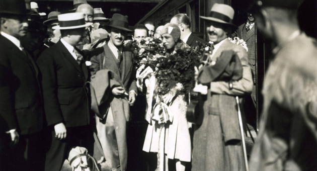 Groep mensen verwelkomt iemand met bloemen in Den Haag.