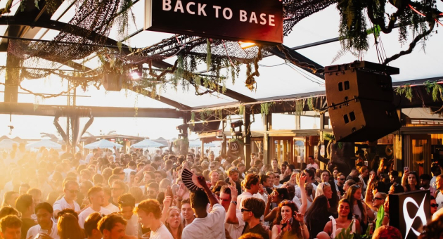 Een druk feest met mensen die dansen bij zonsondergang.