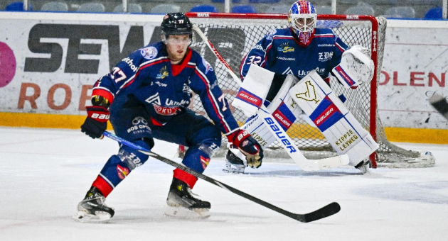 Een ijshockeyspeler van HIJS met puck en keeper op achtergrond