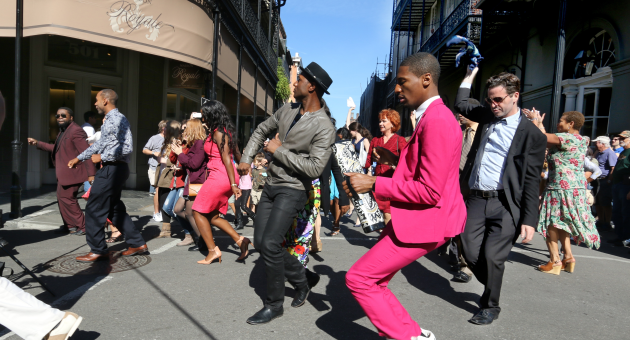 America's Music. Een groep mensen danst vrolijk op straat in een stadsomgeving.