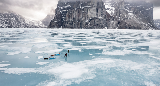 Twee skiërs op een bevroren meer omringd door bergen.