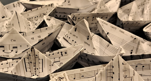 Een verzameling papieren bootjes gemaakt van bladmuziek.
