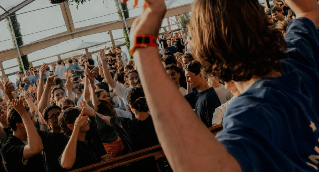 Een menigte viert een evenement met opgestoken handen.