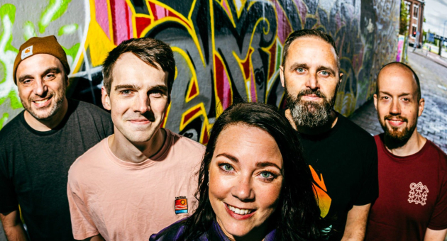 Bandleden Coral Springs poseren vrolijk voor een kleurrijke graffiti muur.