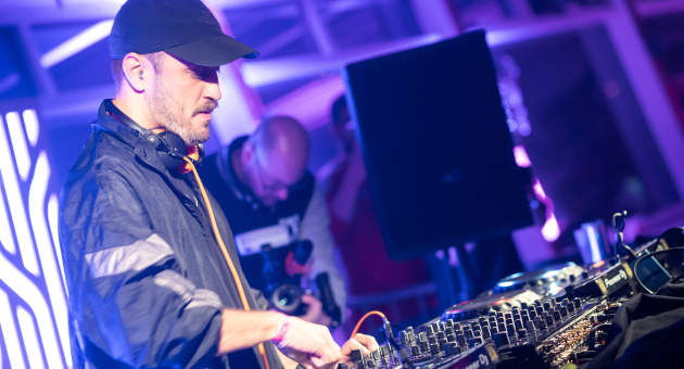 Een DJ draait muziek met een mengpaneel in een clubsetting.