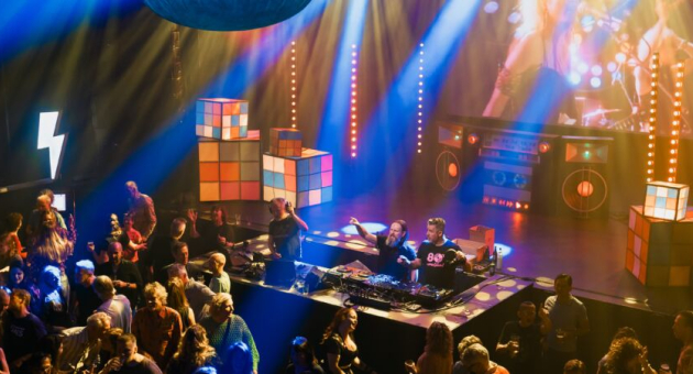 Mensen dansen op een feest met DJ's en kleurrijke decoraties