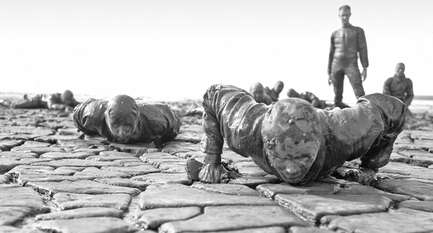 Dag van de Militaire geschiendenis. Mannen in wetsuits doen push-ups op een klei-achtige ondergrond.