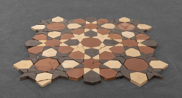 Een geometrisch patroon van keramische tegels in bruin en crème.