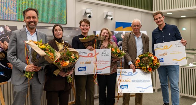Democratie in Woord en Beeld. Zes mensen houden bloemen en cheques tijdens een prijsuitreiking.
