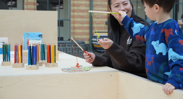 Een vrouw en een kind spelen met kleurrijke speelgoed en tekenmaterialen.