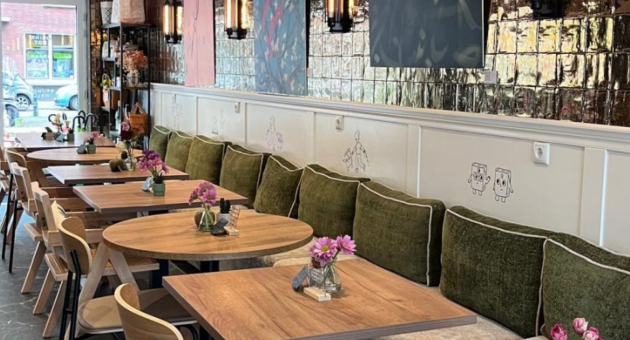 Interior of a café with wooden tables and green sofas.