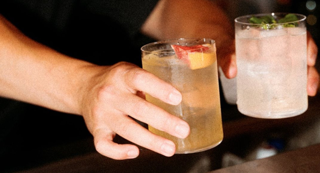 persoon zet twee cocktails op de bar