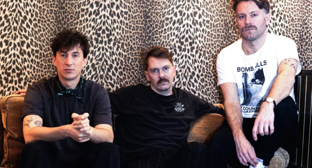 Three men of Ego Dreams sit on a couch against a leopard print wall. Foto: Iris Timmer
