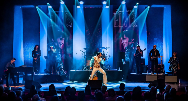 Ein Elvis-Imitator singt auf der Bühne mit Bandmitgliedern.