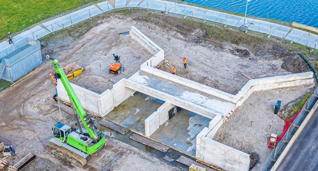 Een bouwplaats met een groene kraan en verbouwde grond.