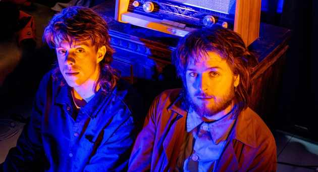 De Dj's zitten op de grond in een ruimte met kleurrijk licht en een vintage radio.