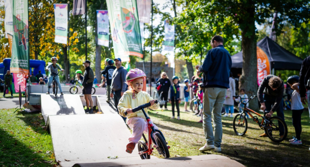 Een meisje rijdt met een fiets op een parcours tussen kijkers.