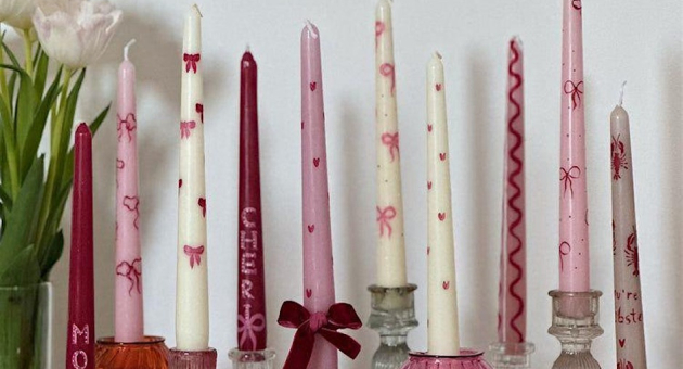 A group of colorful candles in various holders and flowers
