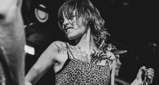 Een vrouw met een leopardprint top danst op het podium.