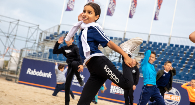 Young girl happily dancing on the beach with other children