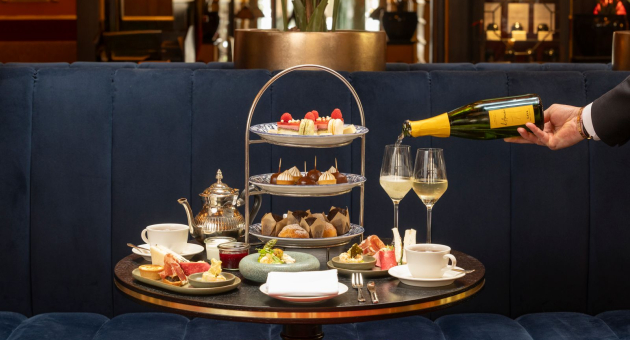 Een elegante tafel met high tea, inclusief thee, gebak en champagne.
