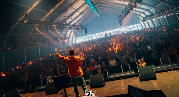 Een zanger staat op het podium voor een vol publiek in een tent. (c) Hollands Live 
