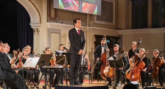 Een solist staat voor een orkest tijdens een concert.