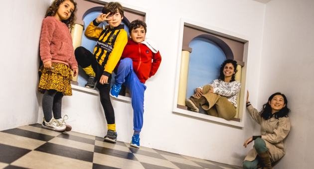 Vijf kinderen en volwassenen poseren in een speelse ruimte