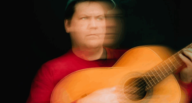 Jake Xerxes Fussell met een gitaar, onscherp door beweging