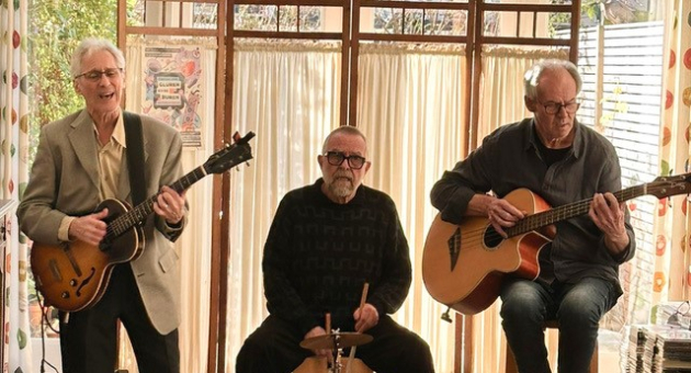 Three musicians perform live music in a cozy space.