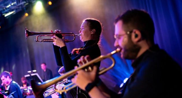 Jong Metropole – Fiesta de Verano. Twee muzikanten spelen trompet op een podium.