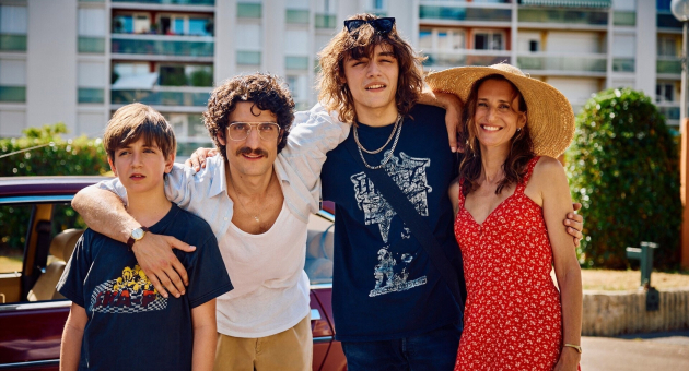 A man, two boys, and a woman pose happily outside.