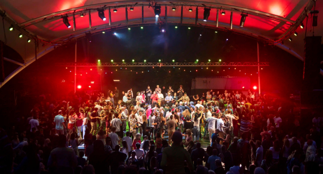 Een druk dansfeest met veel mensen in een tent