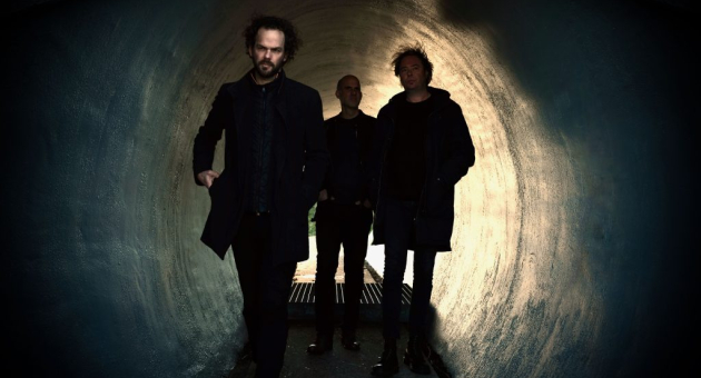 Drie mannen wandelen door een donkere tunnel.