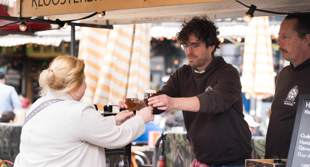 Eine Frau erhält ein Glas Bier von einem Barkeeper.