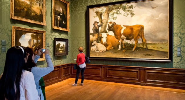 Zaal in het Mauritshuis waar mensen kijken naar en foto's maken van het schilderij De stier van Paulus Potter