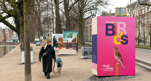 Vrouw loopt met een hond langs tentoonstellingspanelen.