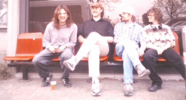 Vier bandleden Lintworm zittend op een bankje, lachend in Den Haag.