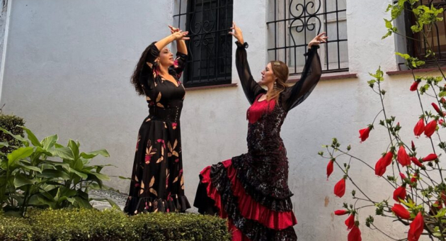 Twee vrouwen in traditionele Flaemnco outfits dansen buiten.