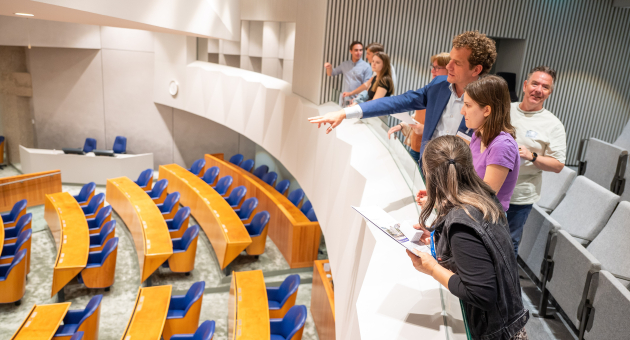 Groep mensen bekijkt de plenaire zaal in de Tweede Kamer.