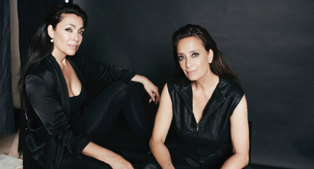 Twee vrouwen, gekleed in zwart, zitten in een studio.