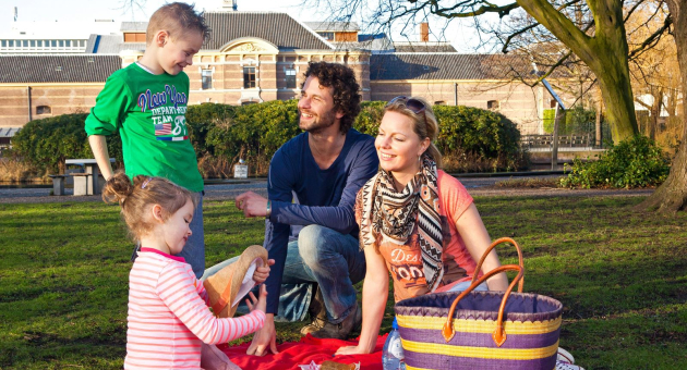 Man, vrouw en twee kinderen genieten van een picknick in de Paleistuin Paleis Noordeinde