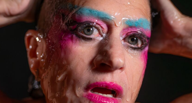 Close-up van een persoon met opvallende make-up en waterdruppels.