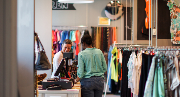 Twee vrouwen in gesprek bij de kassa van de tweedehands kledingwinkel ReShare Store Den Haag.