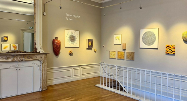 Interieur van een galerie met abstracte schilderijen aan de muur.